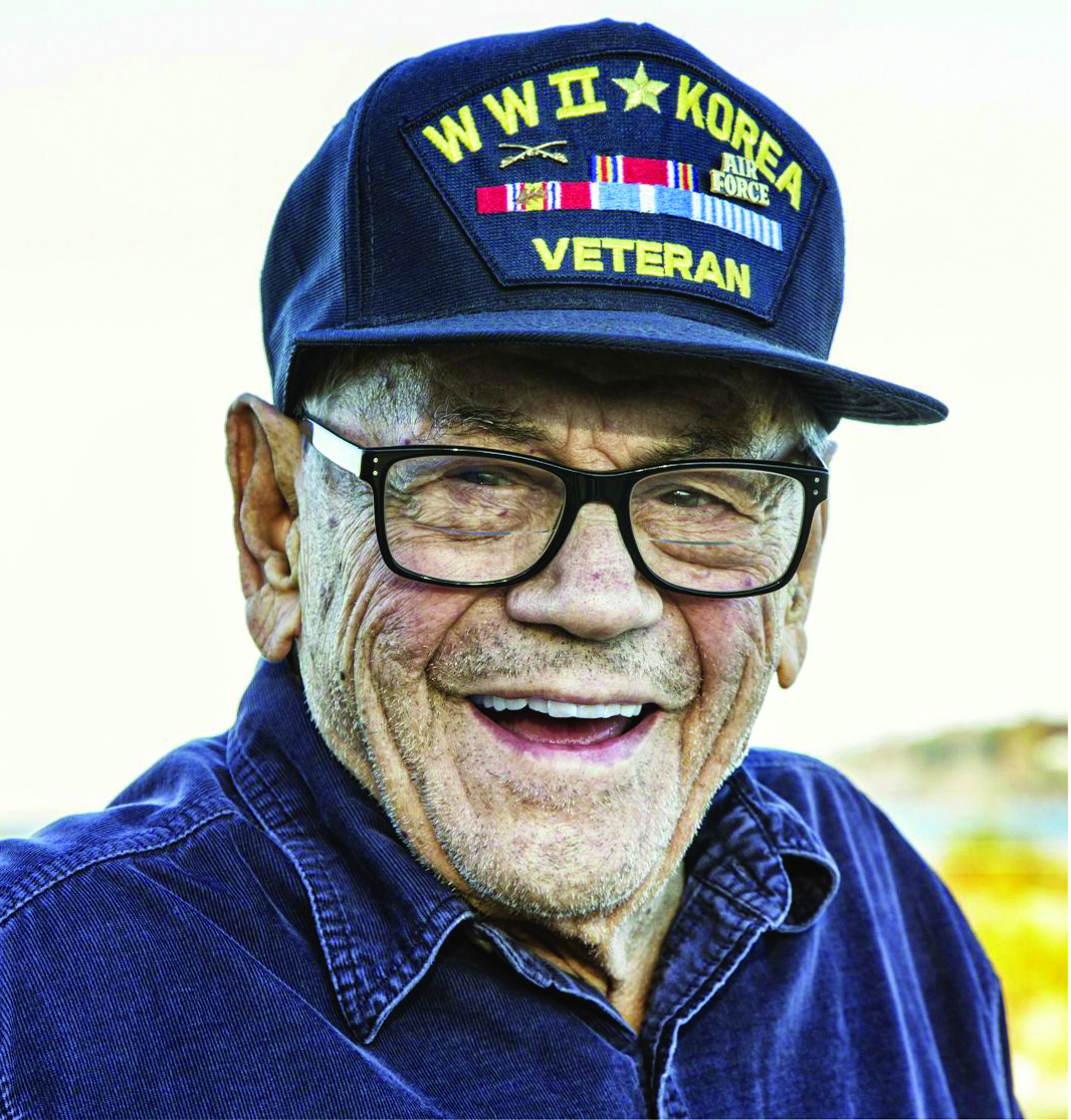 A smiling World War II and Korean War veteran wearing his service cap